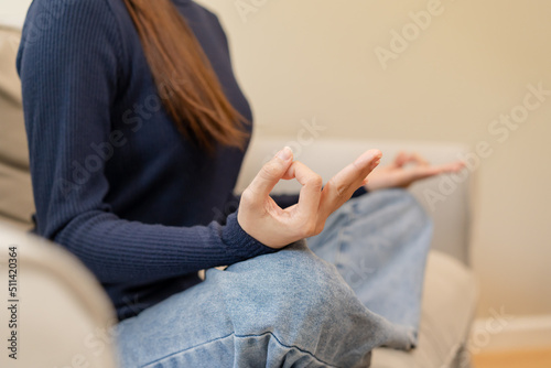 Close up hands of calm pose asian young woman, girl practice sitting, meditating in lotus position on sofa at home, meditation, exercise for wellbeing, healthy care. Relaxation, leisure people. © KMPZZZ