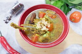 shurpa - oriental soup with vegetables and lamb served in a red bowl topped with fried garlic. 