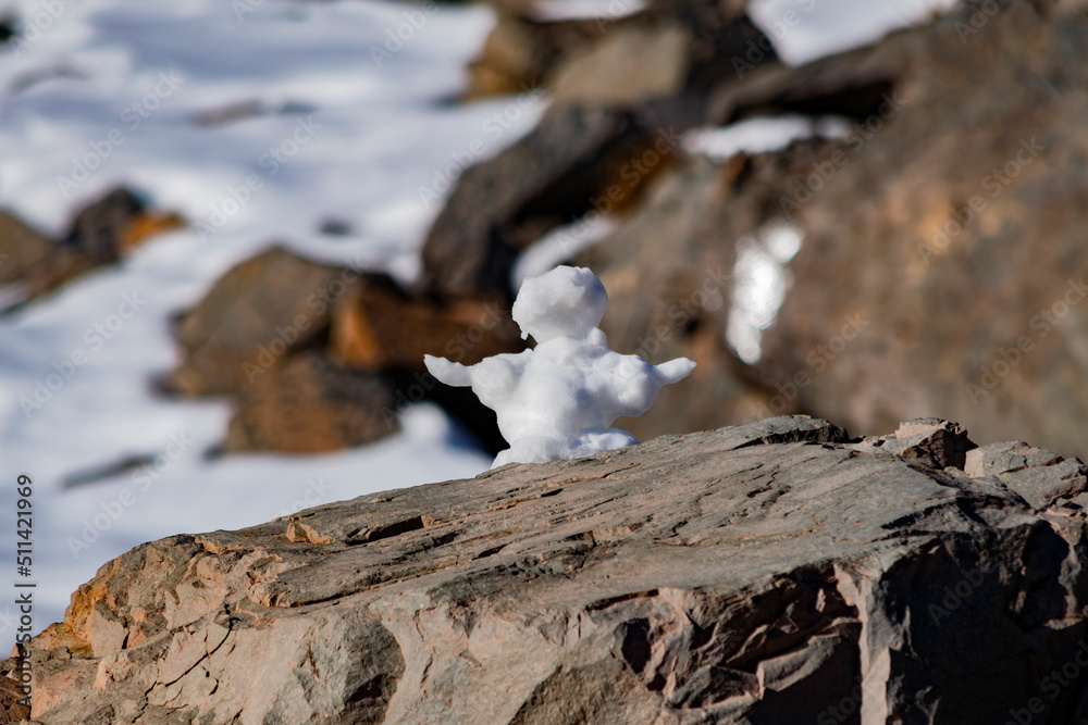snowman on top of a big rock in the snowy mountain snowman on top of a big rock in the snowy mountain