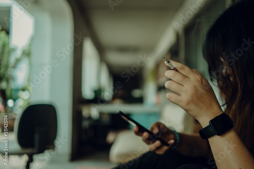 woman in black shirt holding smartphone and stressing about work hand smoking cigarette unhealthy lifestyle concept