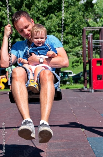 Father swinging with his little boy on playground