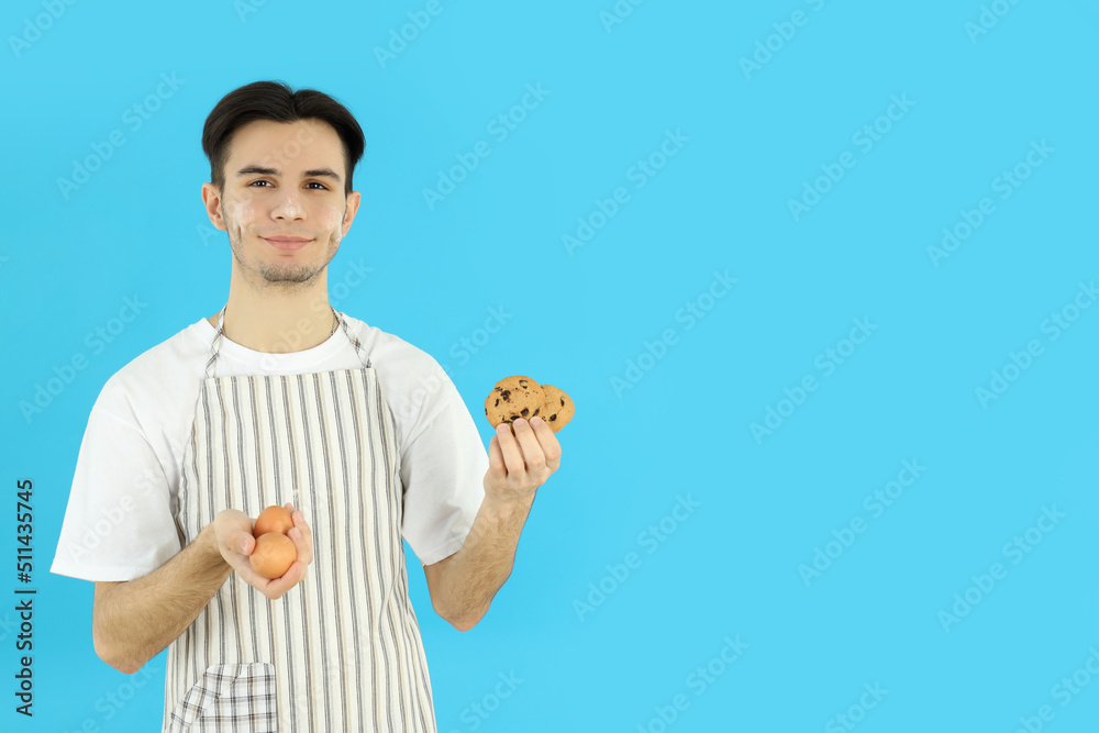 Concept of cooking, young man in apron on blue background Concept of cooking, young man in apron on blue background