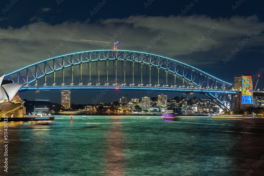 Naklejka premium Colourful Light show at night on Sydney Harbour NSW Australia. The bridge illuminated with lasers and neon coloured lights. Sydney laser light show