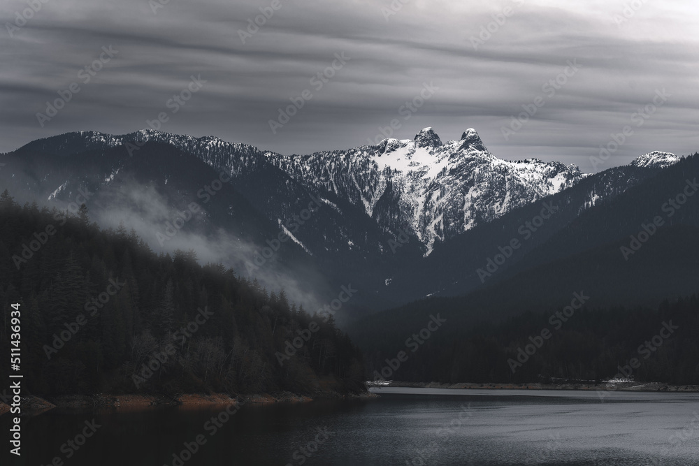Capilano Lake and mountains with Lions peaks that are covered with snow.