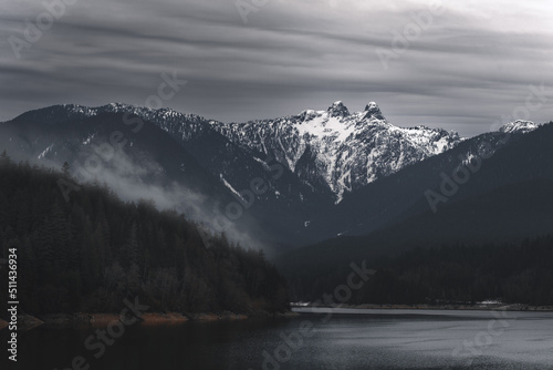 Capilano Lake and mountains with Lions peaks that are covered with snow.
