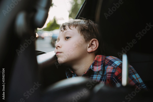 Sad bored caucasian boy travelling by car sitting by open window