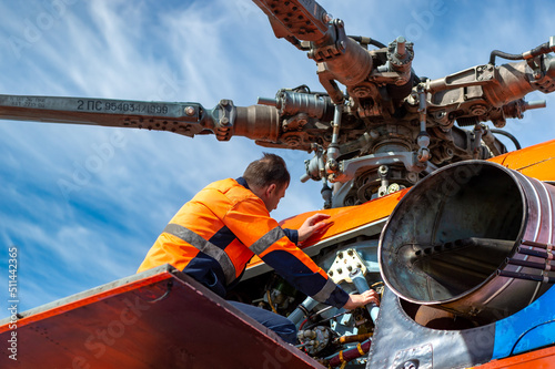 Technician - ground personnel at the airport checks the engine of the helicopter. Helicopter maintenance.