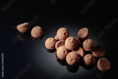 Chocolate truffles on a black reflective background.