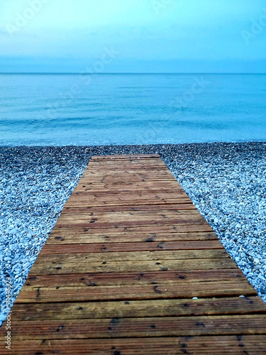 Fotografering cheminement en planche sur une plage de galets pour rejoindre la mer méditerrané