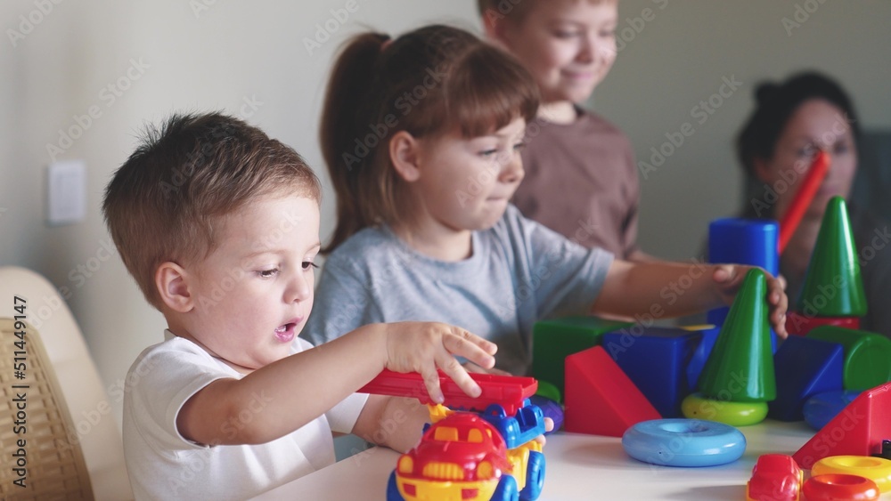 little boy and baby girl play in kindergarten. a group of children play toys cubes and cars on the table in kindergarten. happy family preschool education concept. indoor nursery baby toddler home little boy and baby girl play in kindergarten. a group of children play toys cubes and cars on the table in kindergarten. happy family preschool education concept. indoor nursery baby toddler home