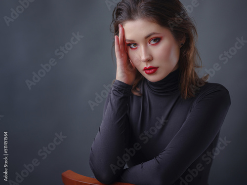 seductive asian woman with red lips in black turtleneck isolated on dark grey