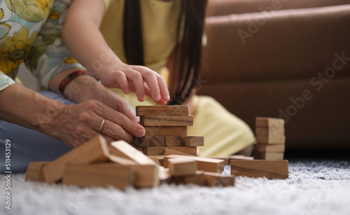 Cropped shot grandmother playing wooden blocks with her little grandchild in living room ,spending happy time on weekend together.