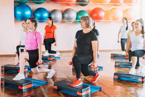 Group of women are engaged in step aerobics with dumbbells in their hands. photo