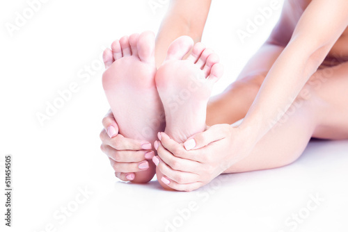 Feet Therapy Concepts. Closeup Image of Soft and Beautiful Female Foot While Hands Touching Heels And Massaging Placed Over Pure White Background. © danmorgan12