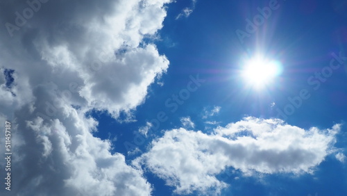 background of white thick cumulus clouds on a blue sky on a sunny bright day © belavinstock