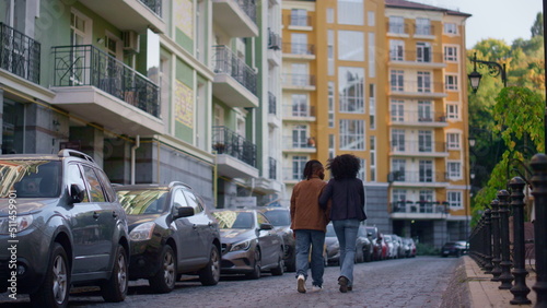 Fototapeta Naklejka Na Ścianę i Meble -  Married couple walking together at modern city residential complex rear view.