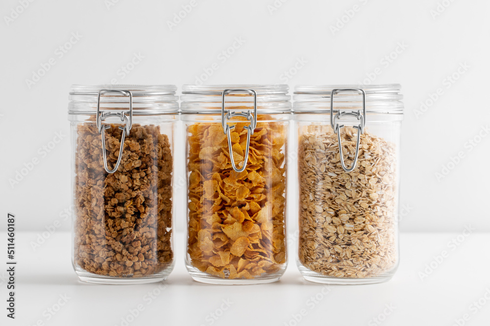 food, healthy eating and diet concept - jars with oat, corn flakes and granola on white background food, healthy eating and diet concept - jars with oat, corn flakes and granola on white background