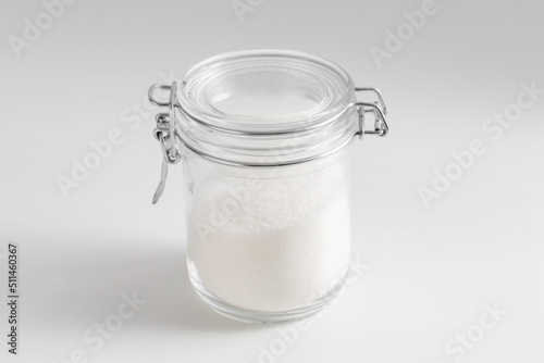 food storage, cooking and unhealthy eating concept - close up of white sugar glass jar on table