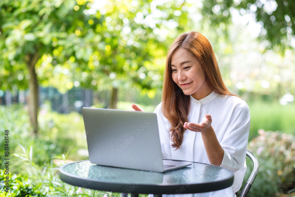 Portrait image of a young woman using laptop computer for video call and working online in the outdoors Portrait image of a young woman using laptop computer for video call and working online in the outdoors