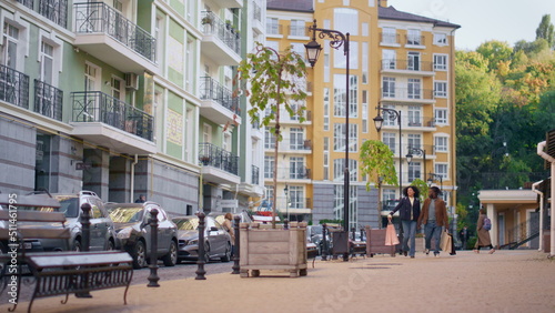 Smiling family walking street holding bags in hands. Modern residential area.