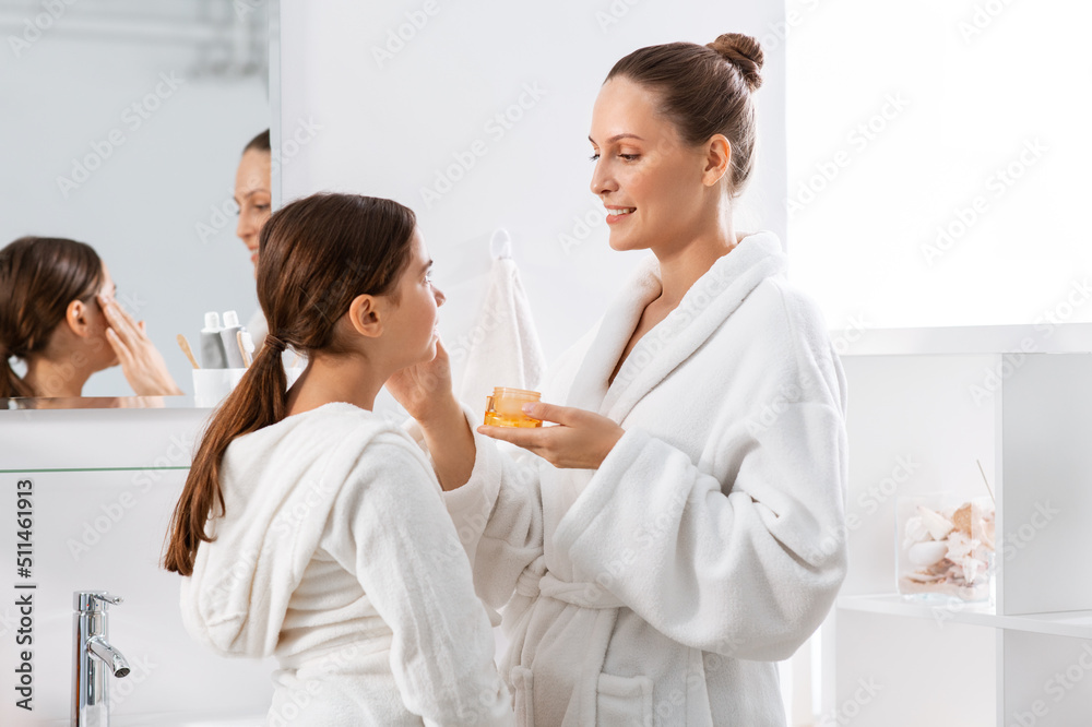 beauty, hygiene, morning and people concept - happy smiling mother and daughter with moisturizer at bathroom beauty, hygiene, morning and people concept - happy smiling mother and daughter with moisturizer at bathroom