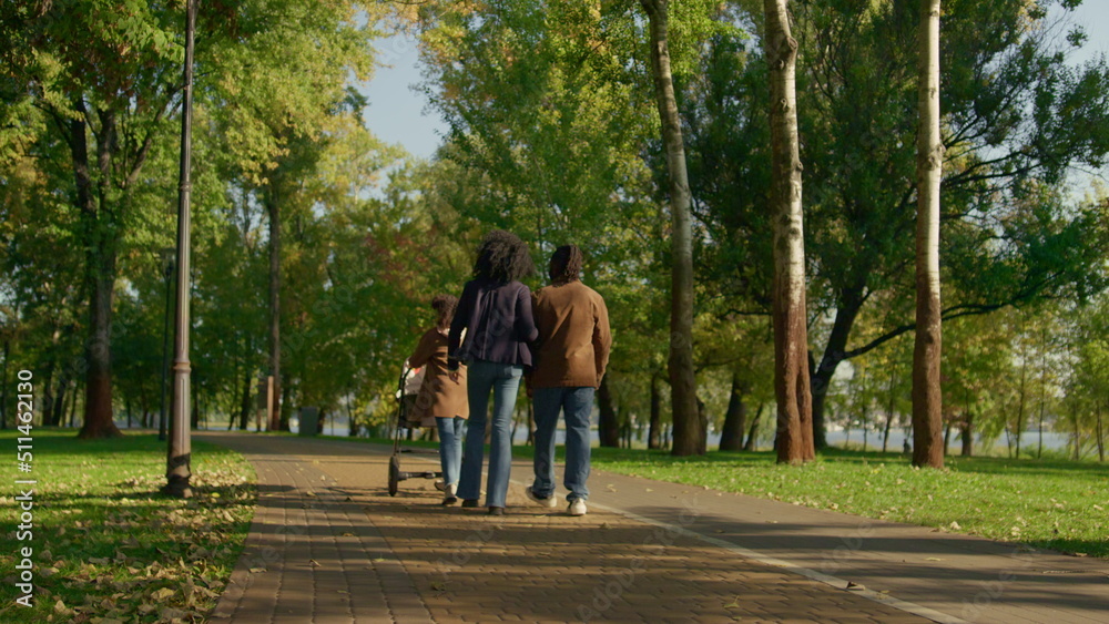 Casual parents walking autumn park rear view. Happy family weekend concept. Casual parents walking autumn park rear view. Happy family weekend concept.