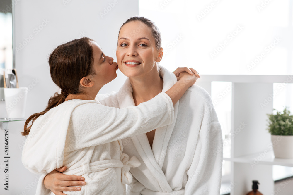 beauty, hygiene, morning and people concept - happy daughter kissing and hugging her smiling mother in bathroom beauty, hygiene, morning and people concept - happy daughter kissing and hugging her smiling mother in bathroom