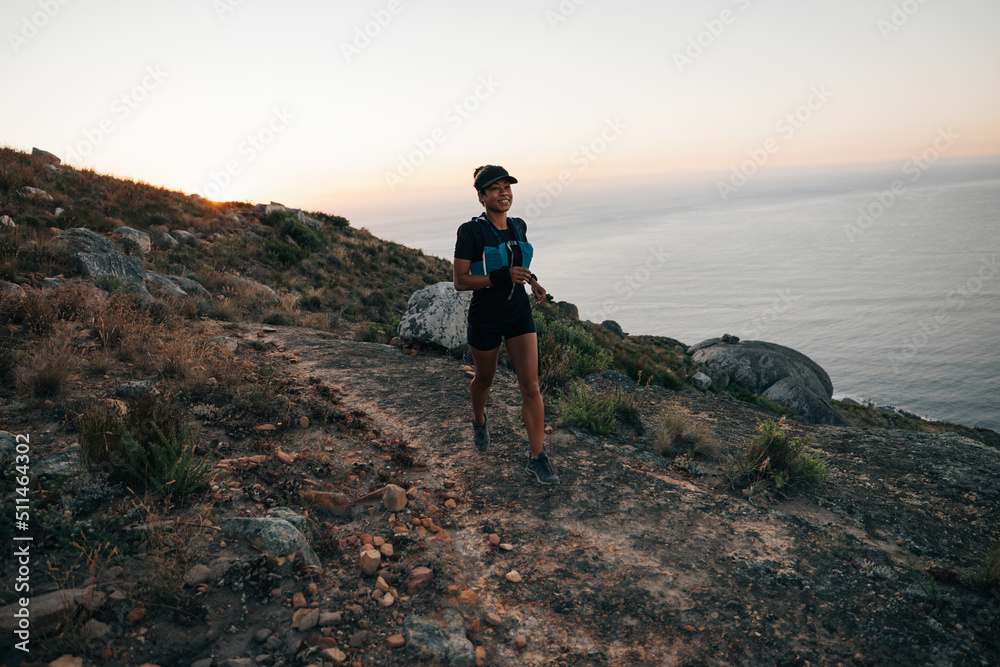 Fototapeta premium Trail runner exercising at sunset on mountain. Woman running on a hill.