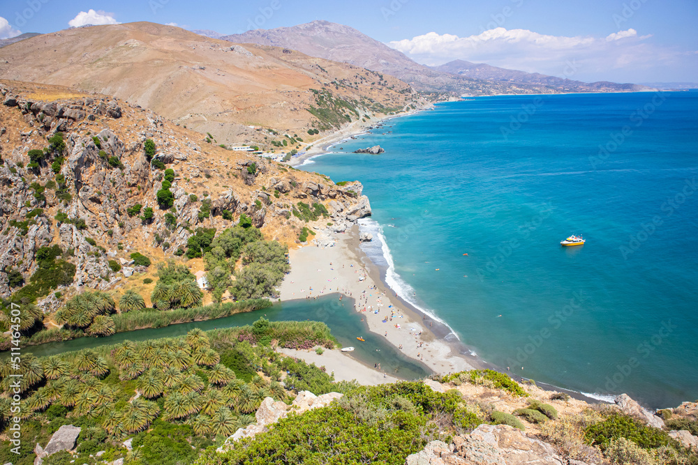 Picturesque Preveli Beach on island of Crete, Greece, Europe. Sunny summer day. Blue sea and sky. Valley seen from above view point. Palm forest, river and beach.