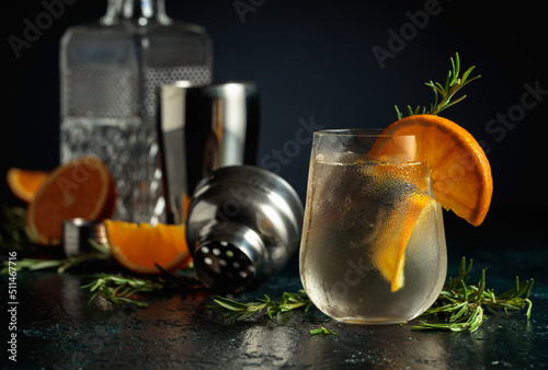 Cocktail gin tonic with ice, orange, and rosemary.