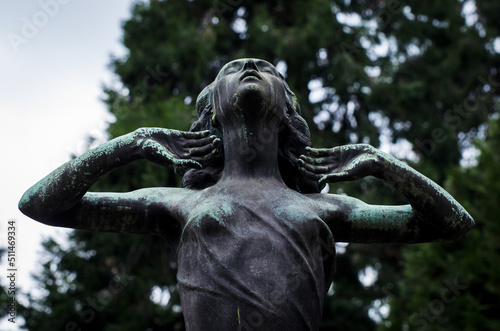 La statua di  bronzo ossidato di una donna sofferente sopra una tomba del cimitero monumentale di Milano photo