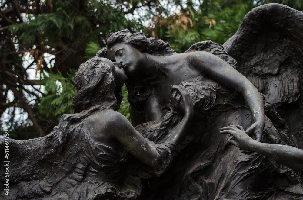 La statua di una donna che bacia un angelo su una tomba del cimitero monumentale di Milano