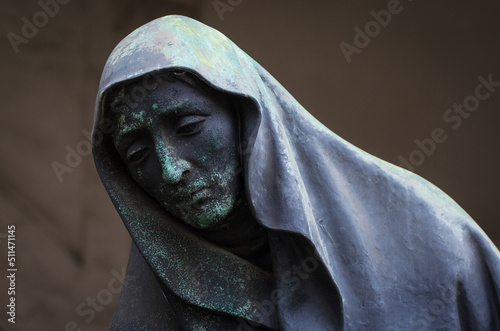 La statua di una donna disperata con la testa coperta da un velo su una tomba del cimitero monumentale di Milano photo
