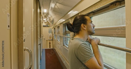 Young attractive tourist, looker out of the window of a moving train at sunset