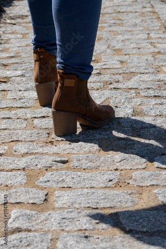 mujer camina con botín de tacón sobre suelo de adoquín 