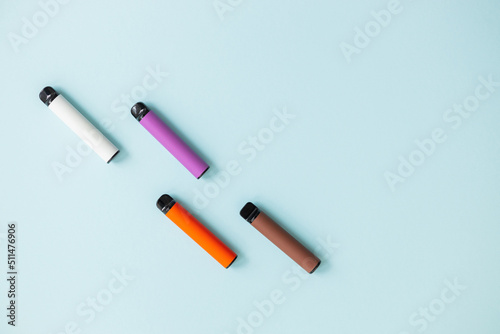 Layout of colorful disposable electronic cigarettes on a blue background. The concept of modern smoking