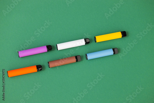 disposable electronic cigarettes with shadow on a green background with copy space. The concept of modern smoking, vaping and nicotine. top view.