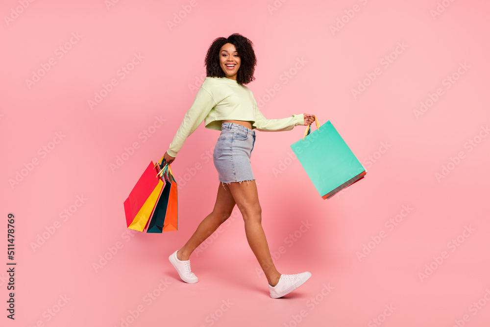Fototapeta premium Full size profile side photo of young girl go hold shopping bags store isolated over pink color background