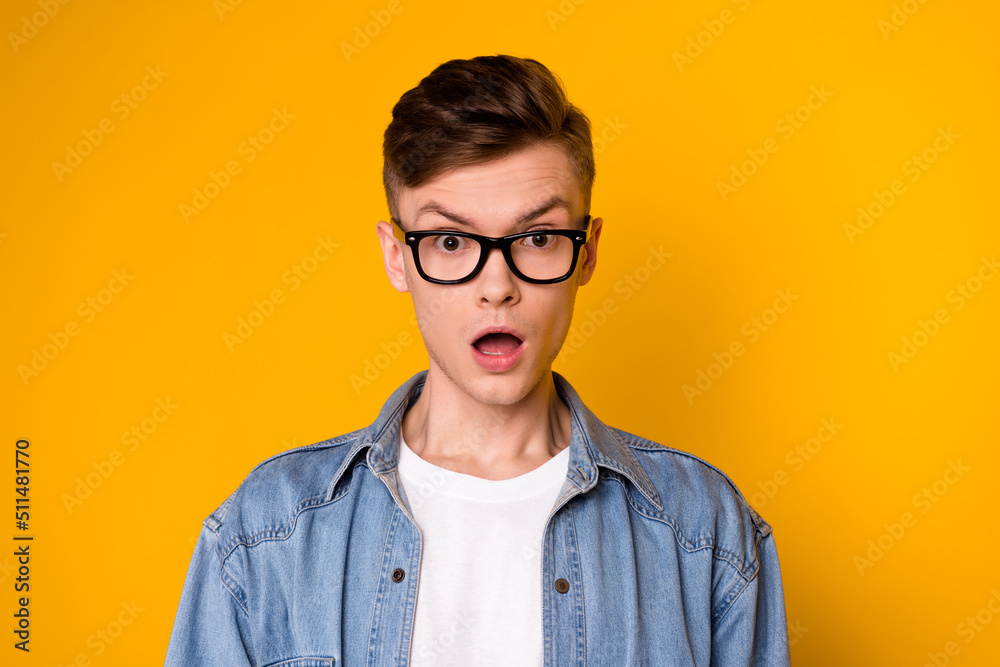 Photo of young astonished guy open mouth fake information eyewear isolated over yellow color background