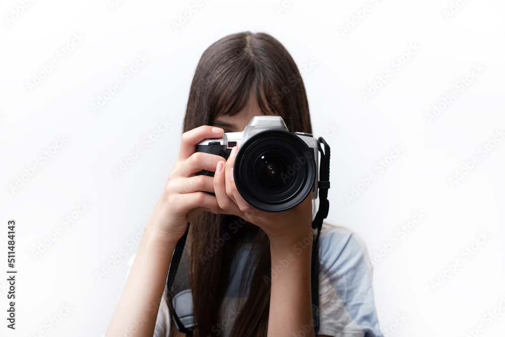 Teenage young woman taking pictures on professional camera. Portrait of a teen israeli photographer covering her face with the camera. White background Teenage young woman taking pictures on professional camera. Portrait of a teen israeli photographer covering her face with the camera. White background