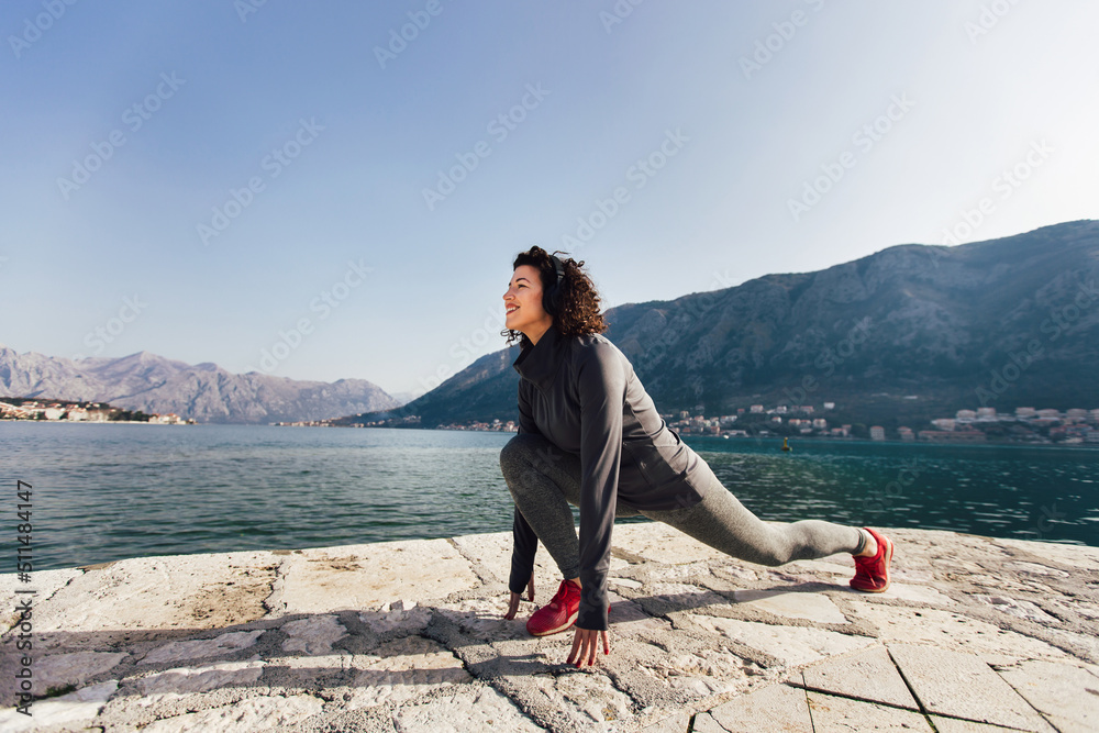 Athletic young woman with curly hair doing exercises on the beach Athletic young woman with curly hair doing exercises on the beach