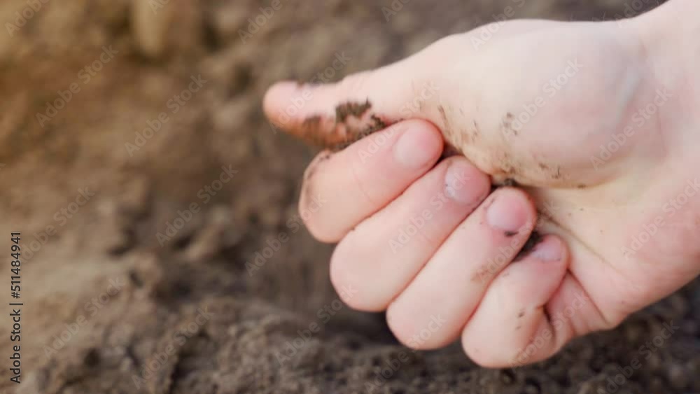 The hand rubs soft loose soil close-up. The soil is ready for planting plants in the spring in the garden