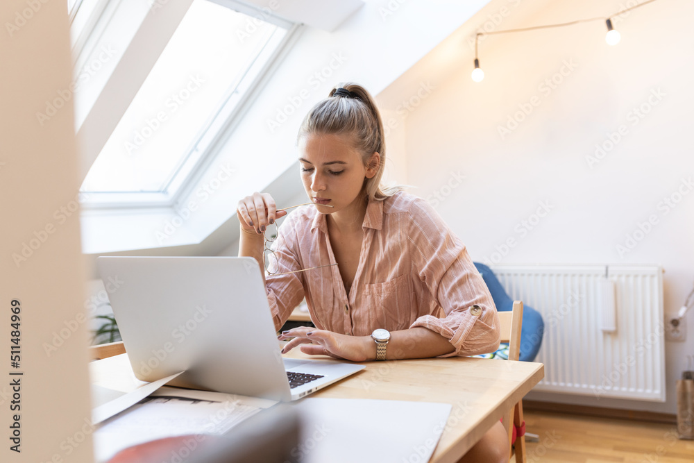 Pretty female sitting at home and using laptop at the morning.Studying. Pretty female sitting at home and using laptop at the morning.Studying.