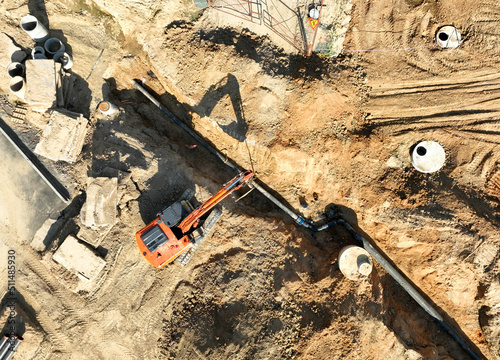 Sewage drainage system mounting at construction site. Excavator during laying sewer pipe and main systems. Civil infrastructure, water lines, sanitary sewers and storm sewers. Laying sewer pipes. photo