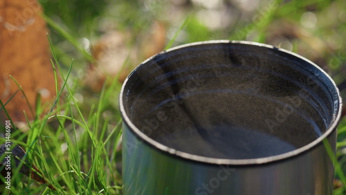 Hot beverage metal cup standing green forest lawn sunny autumn day closeup © stockbusters