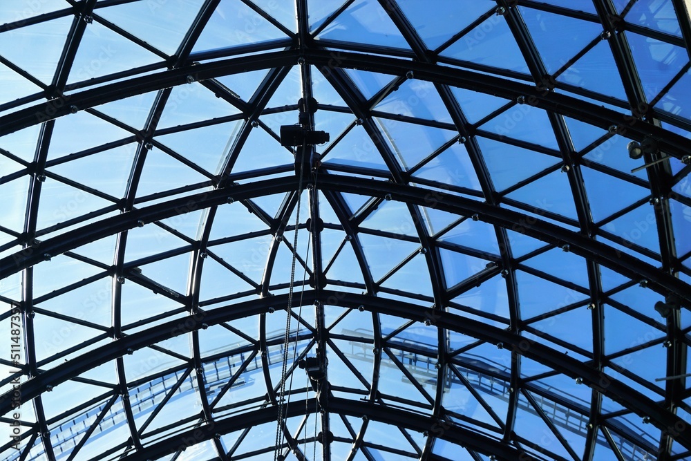 Glasdach mit Rundbögen aus schwarzem Stahl vor blauem Himmel bei Sonne im Frühling Glasdach mit Rundbögen aus schwarzem Stahl vor blauem Himmel bei Sonne im Frühling