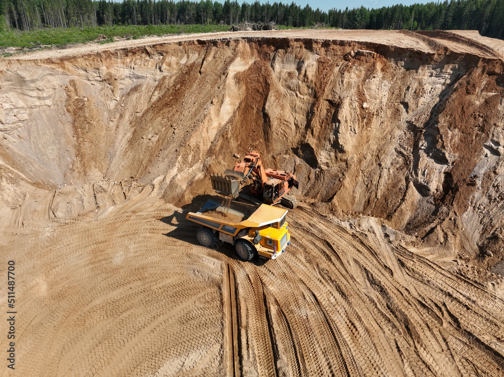 Excavator load sand into mining truck in opencast. Mining excavator in open pit during sand mining. Excavator on development sand pit. Earth Mover load soil in haul truck. Earthmover on sand mining.