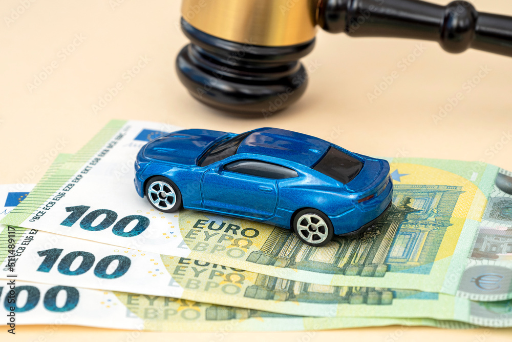 Gavel of judge, car model and 100 euro banknotes on the table in court, concept picture