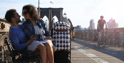 Young family with a baby stroller walks along the Brooklyn Bridge in New York USA