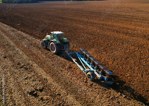 Tractor plowing field. Tractor plow soil cultivating. Cultivated land and soil tillage. Agricultural tractor on farm field cultivation. Tractor disk harrow plowing farm field. Agronomy and agrarian..